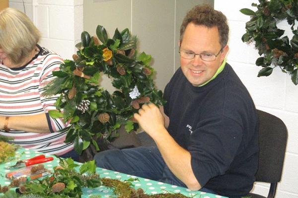 Man at workshop holding Christmas wreath.