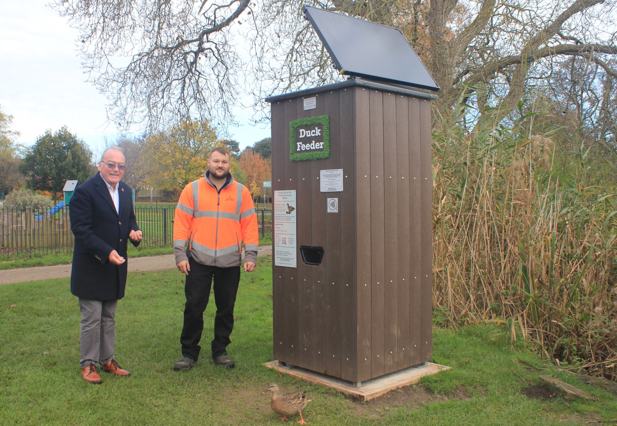 A picture of Bob Harrison of Lichfield Litter Legends (left) and Chris Hammant, Parks and Open Spaces Supervisor, feeding a duck using the new dispenser in Beacon Park.