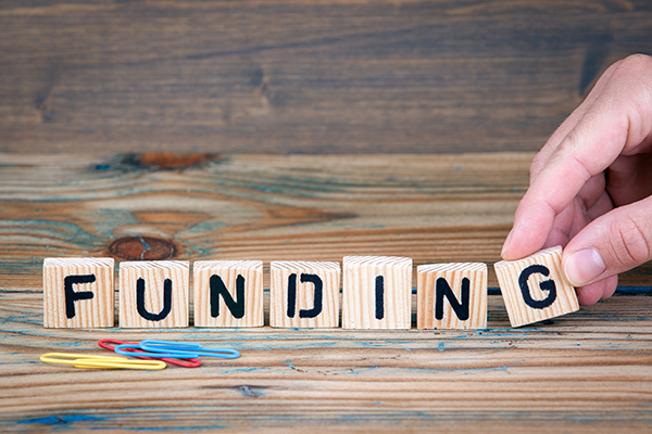 A photo of wooden blocks spelling the word funding.