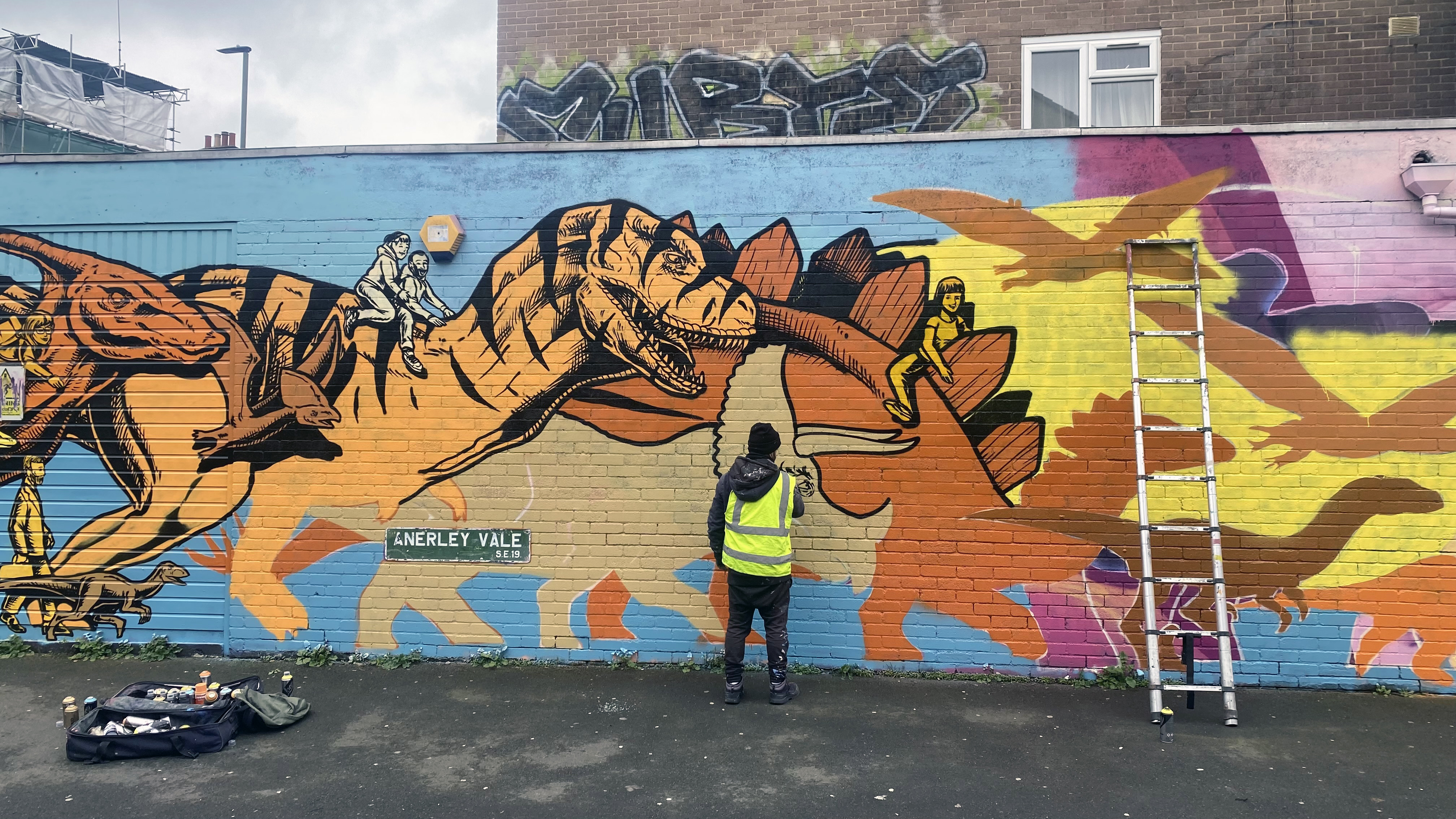 A picture of Street artist and muralist Nacho Welles hard at work on a mural in London.