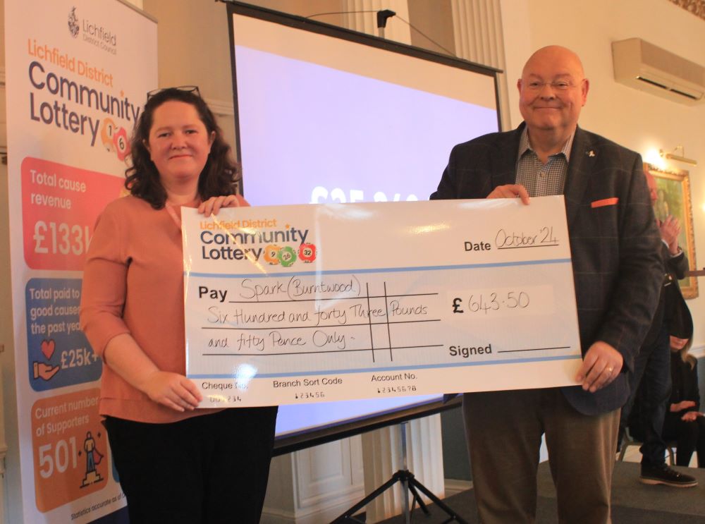 A picture of Esther Allen, CEO of Spark receiving a cheque from Councillor Richard Cox on behalf of Lichfield District Community Lottery.