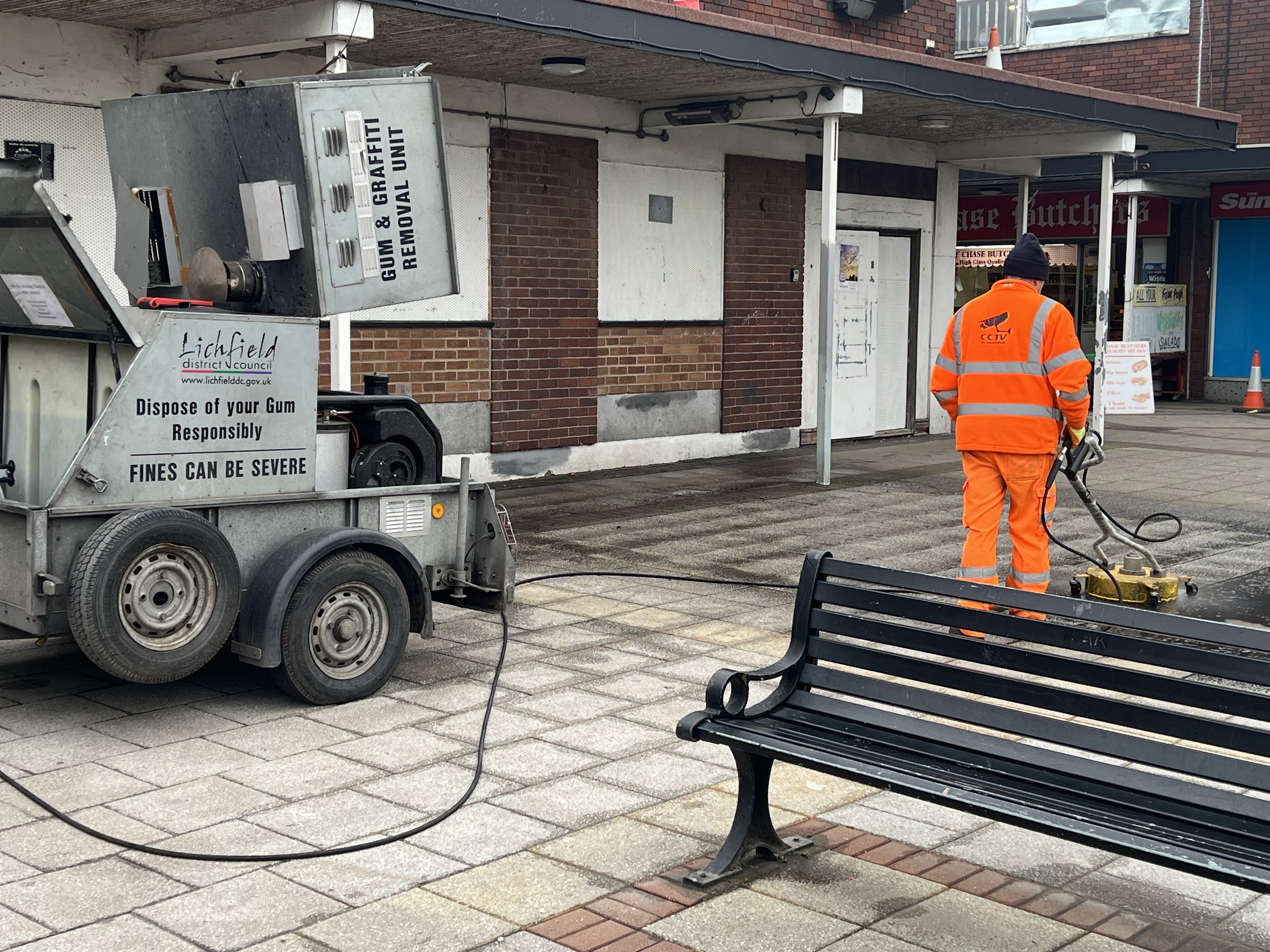 A picturre of a member of Lichfield District Council’s Streetscene team jet-washing the floor surface at Burntwood Shopping Centre.