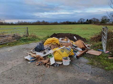 bag of fly tipped rubbish at the gateway to a field